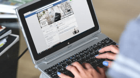 woman using facebook on laptop